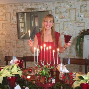 A woman holding a candle in front of a christmas table.