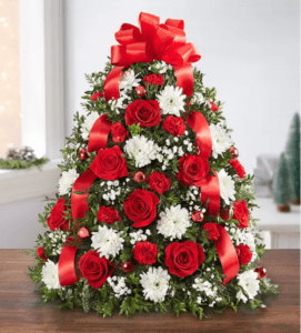 A christmas tree arrangement with red roses and white daisies.