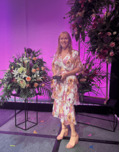 A woman standing in front of a flower arrangement.